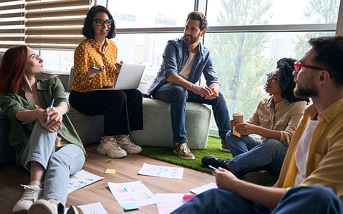 Smiling, multiracial group of business professionals collaborating in a modern office, engaged in a planning session for a startup project.