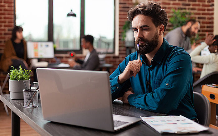 Pensive businessman in a modern office, looking at a computer screen with financial data.