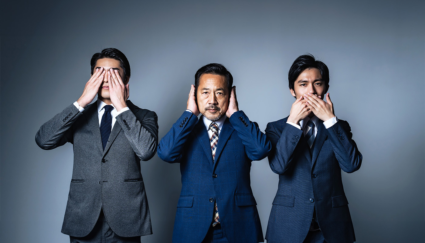 Three businessmen in suits, each covering either their eyes, ears or mouth with their hands, symbolizing the concept of &ldquo;see no evil, hear no evil, speak no evil&rdquo; in a corporate setting.